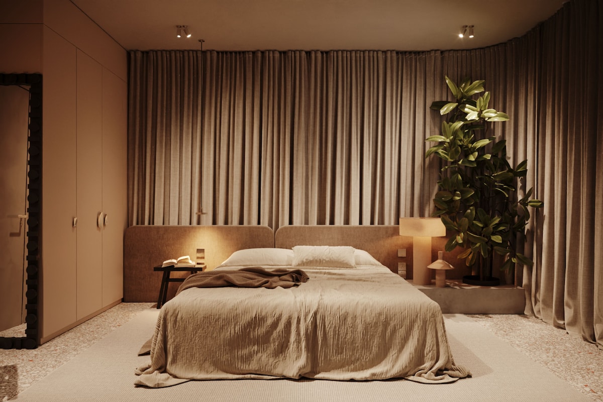 Un dormitorio con una cama grande, una mesita de noche, una lámpara y una planta en maceta.