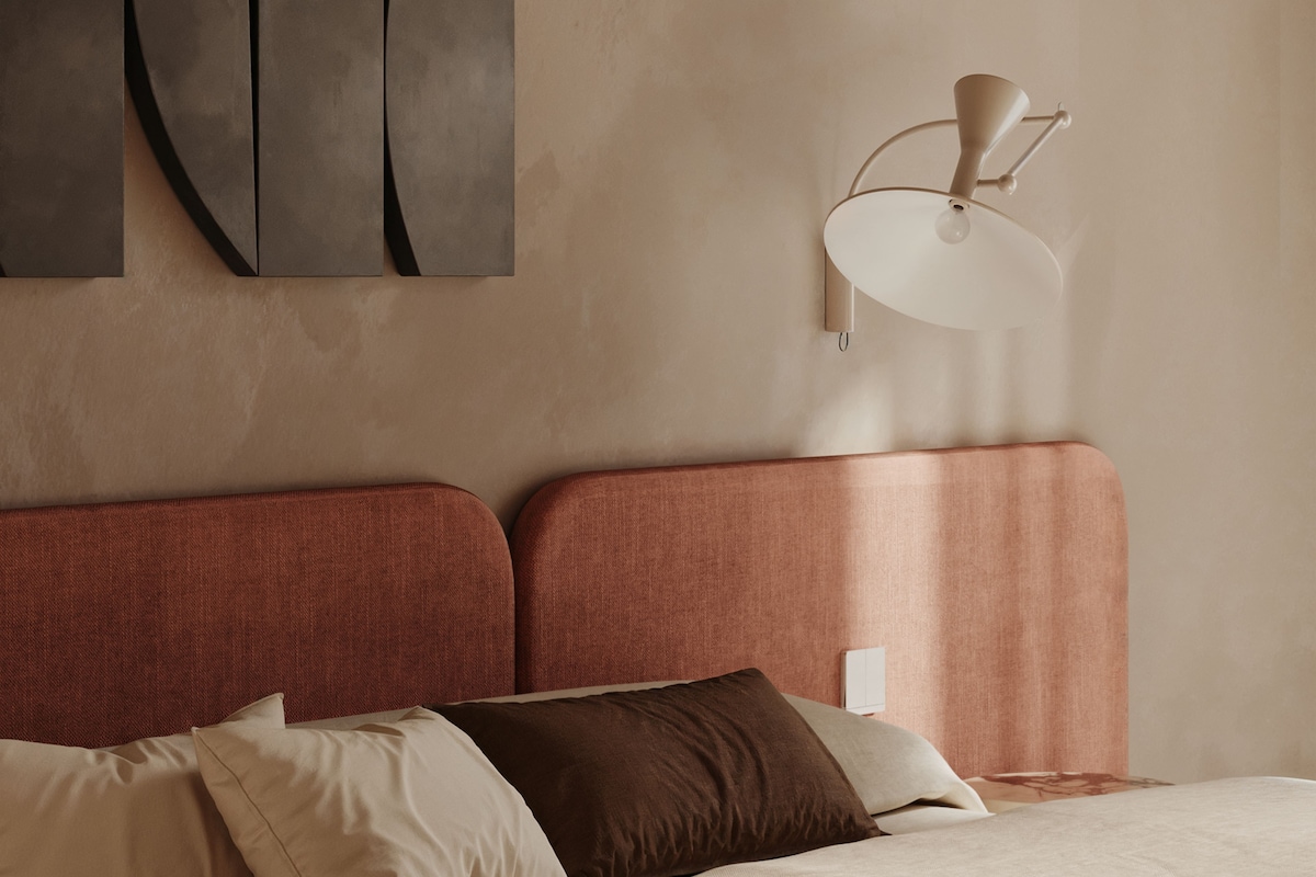 Un dormitorio con cama, almohadas, una lámpara de pared y arte abstracto.