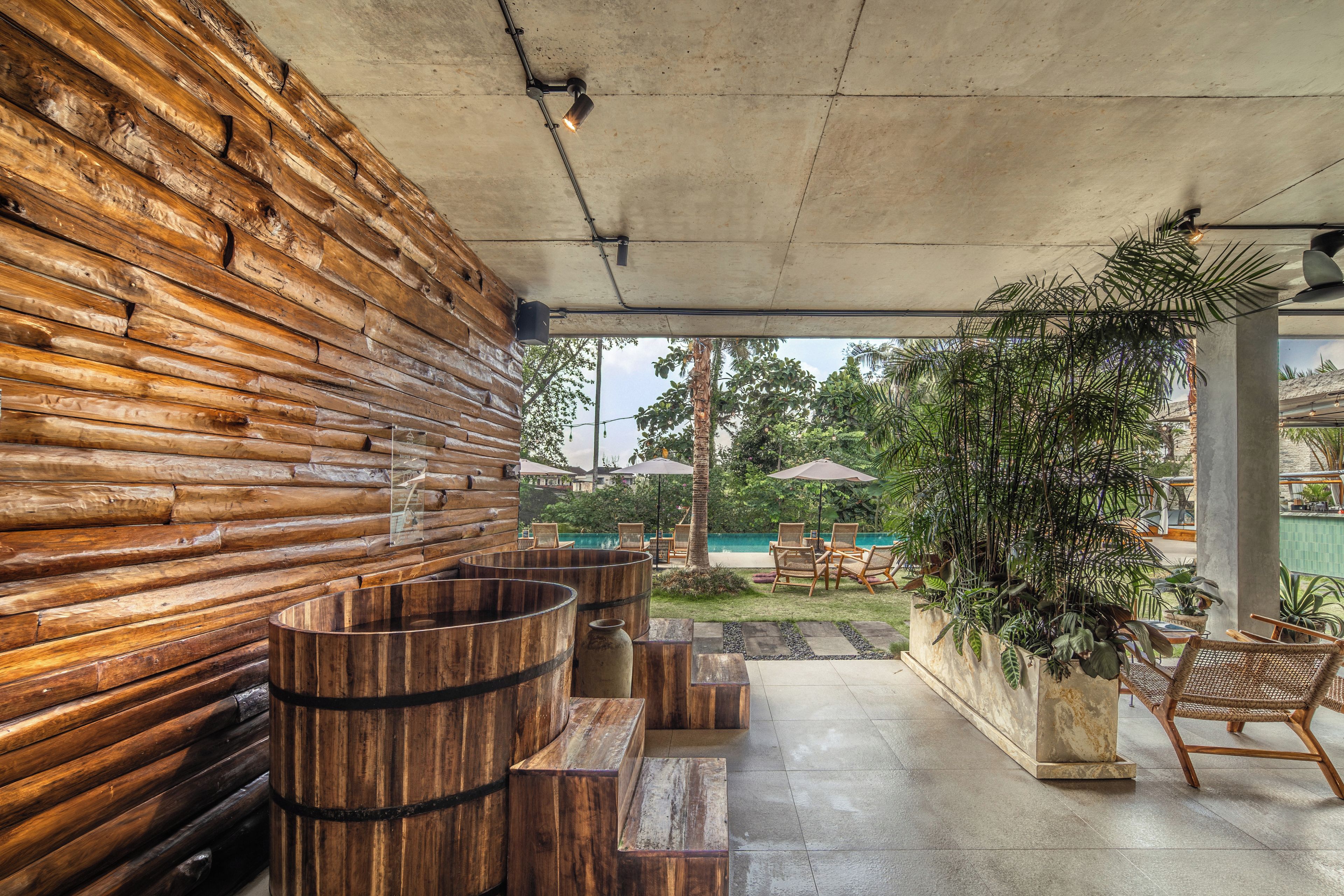 Una pared de troncos de madera, un barril de madera y una zona de estar con sillas y una mesa.