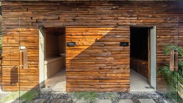 Una cabaña de troncos con dos puertas de madera que dicen 'HAMMAM' y 'SAUNA'.