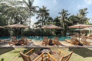 A poolside area with lounge chairs and umbrellas, surrounded by lush greenery. - Saneca Resort Ubud (Ubud)
