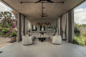 An open-plan living area with a ceiling fan, two sofas, a coffee table, and a dining table. - Saneca Resort Ubud (Ubud)