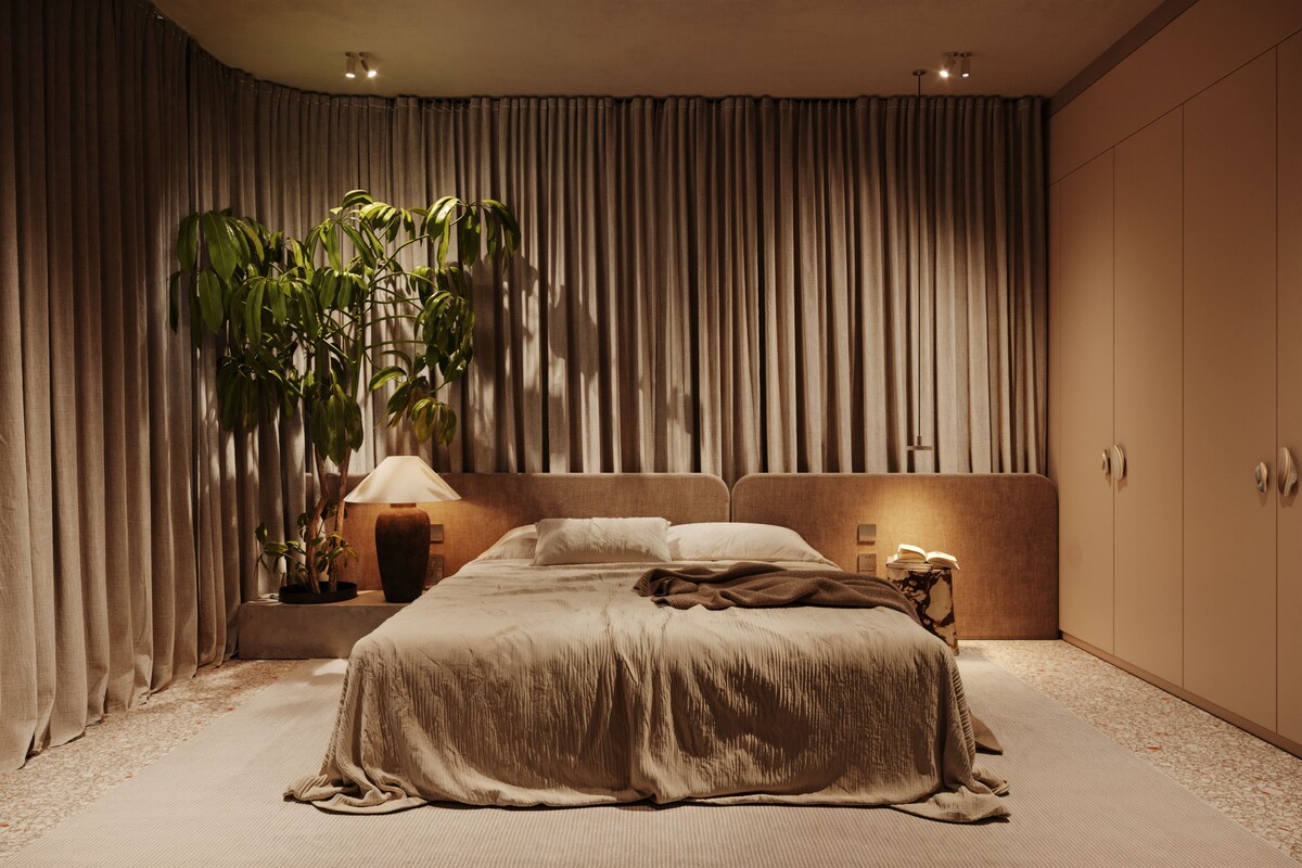 Un dormitorio con una cama grande, una mesita de noche con lámpara, una planta en maceta y un armario.