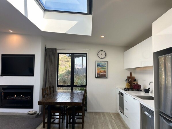 Eine moderne Küche mit Essbereich, Kamin und großem Fenster.