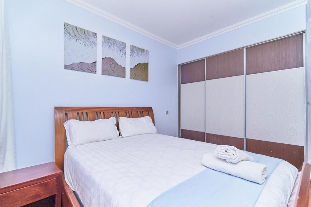 Un dormitorio con una cama de madera, un armario y tres obras de arte colgadas en la pared.