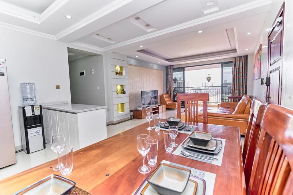 Quarto de hotel moderno com área de jantar, cozinha e varanda com vista para a cidade.