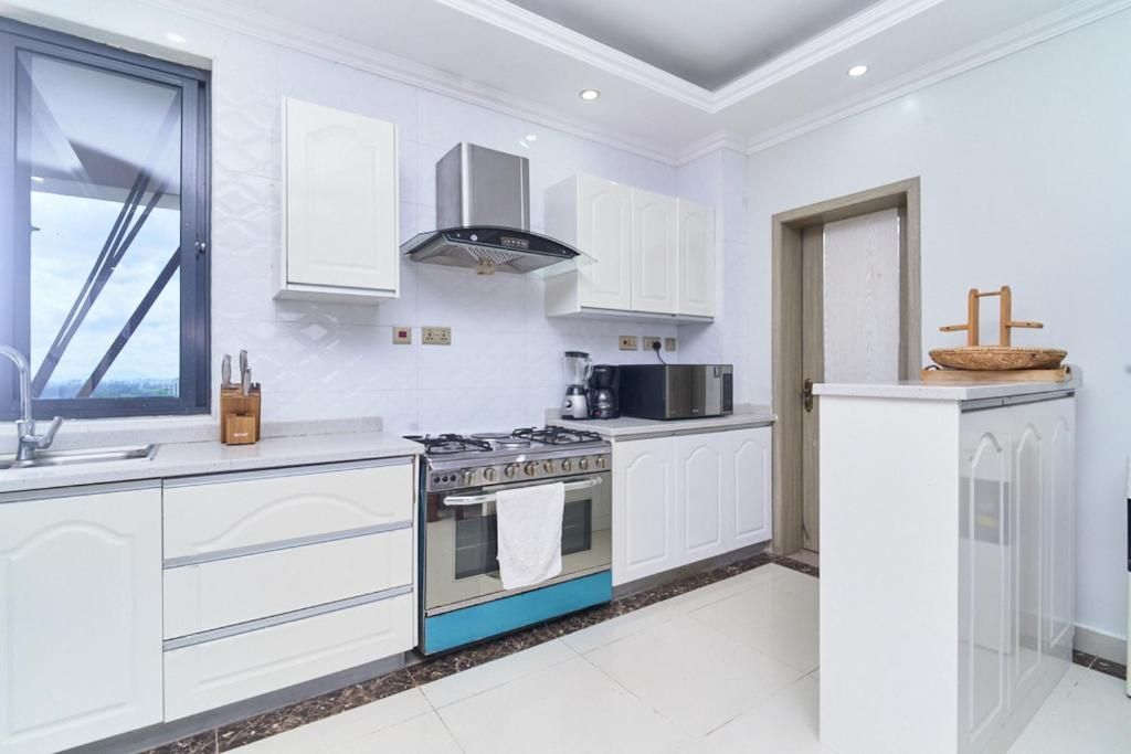 Una cocina moderna con armarios blancos, estufa a gas, microondas y horno empotrado.