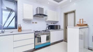 Una cocina moderna con armarios blancos, estufa a gas, microondas y horno empotrado.