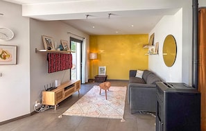 A living room with a sofa, a TV, a fireplace, a wooden cabinet, and a patterned rug. - Maison proche Aix-en-Provence (Le Tholonet)