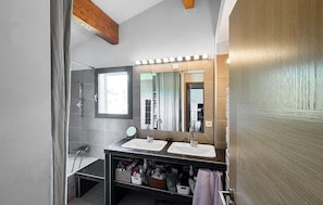 Een moderne badkamer met twee wasbakken, een spiegel en een douche.
