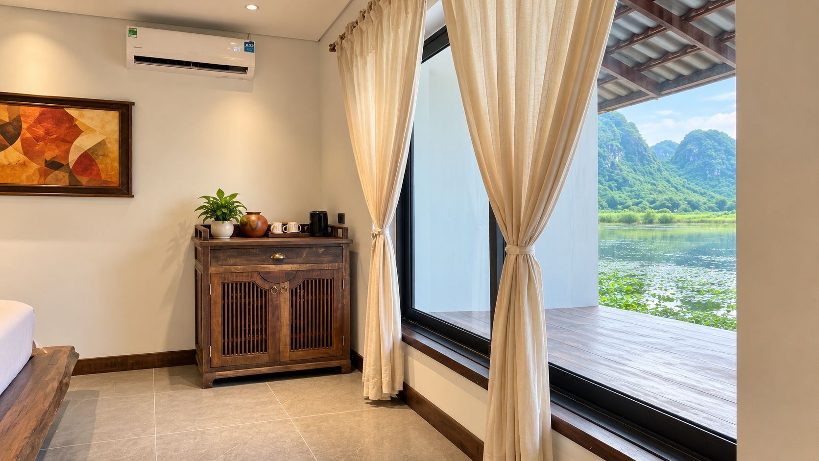 A hotel room with a wooden cabinet, a painting, and a window with curtains.