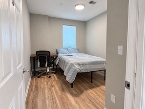 Un dormitorio con una cama, un escritorio y una silla.