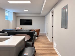 Una sala de estar moderna con un sofá, una mesa de comedor y un televisor montado en la pared.