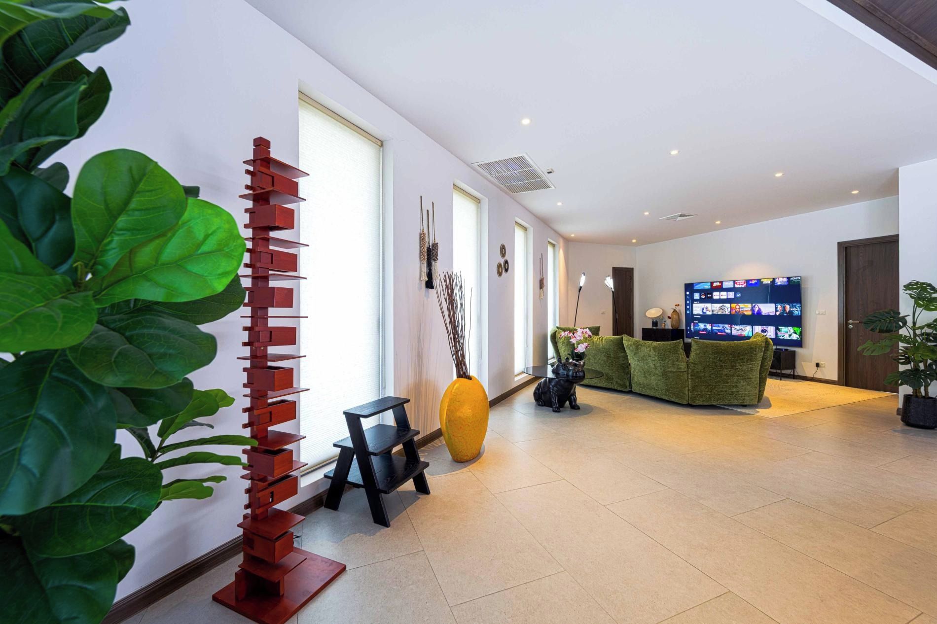 A modern hotel lobby with a reception desk, a large flat-screen TV displaying various channels, and a green sofa.