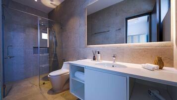A modern bathroom with a glass shower enclosure, a toilet, a white vanity with a mirror, and a sink.