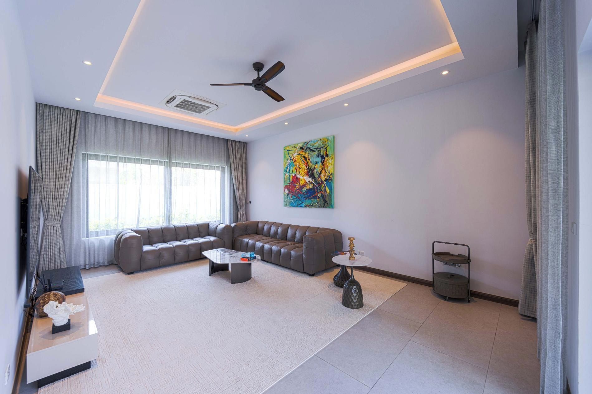 A modern living room with a sectional sofa, a coffee table, and a ceiling fan.