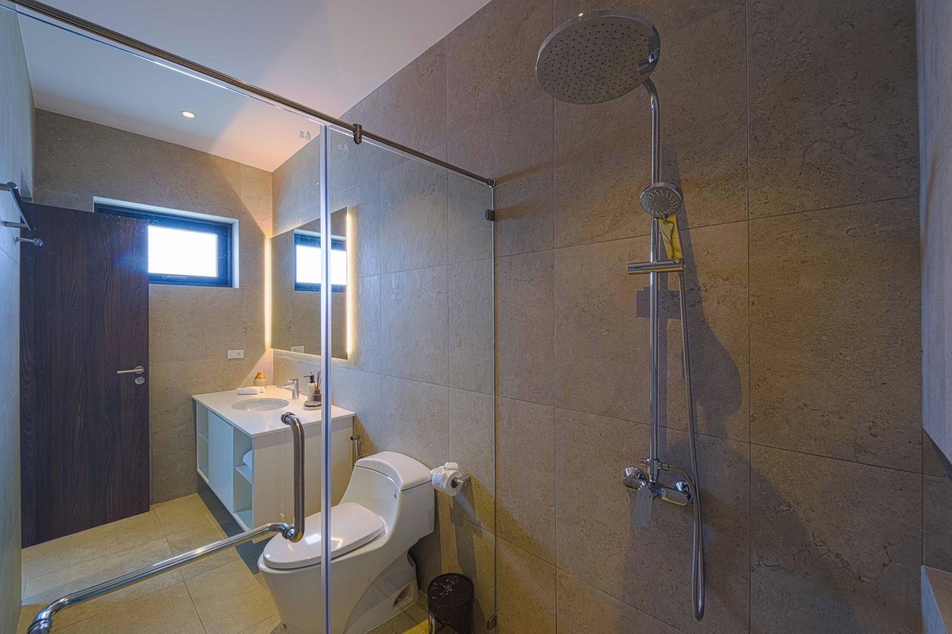 A modern bathroom with a glass shower enclosure, a toilet, and a sink.