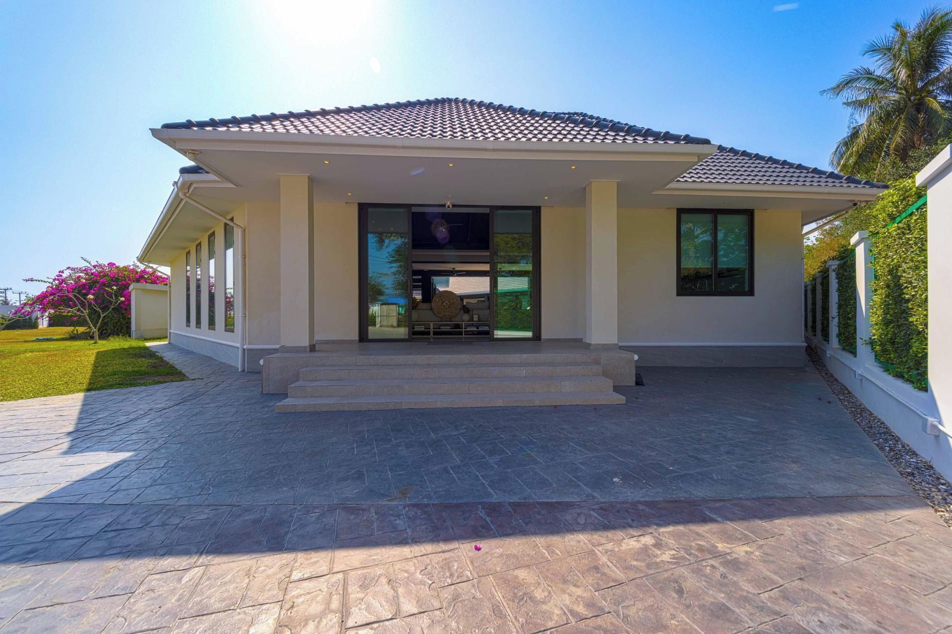 A modern house with a tiled roof, a front porch, and a paved driveway.