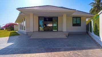 A modern house with a tiled roof, a front porch, and a paved driveway.