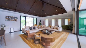 A spacious living area with a large sectional sofa, a coffee table, and a ceiling fan.