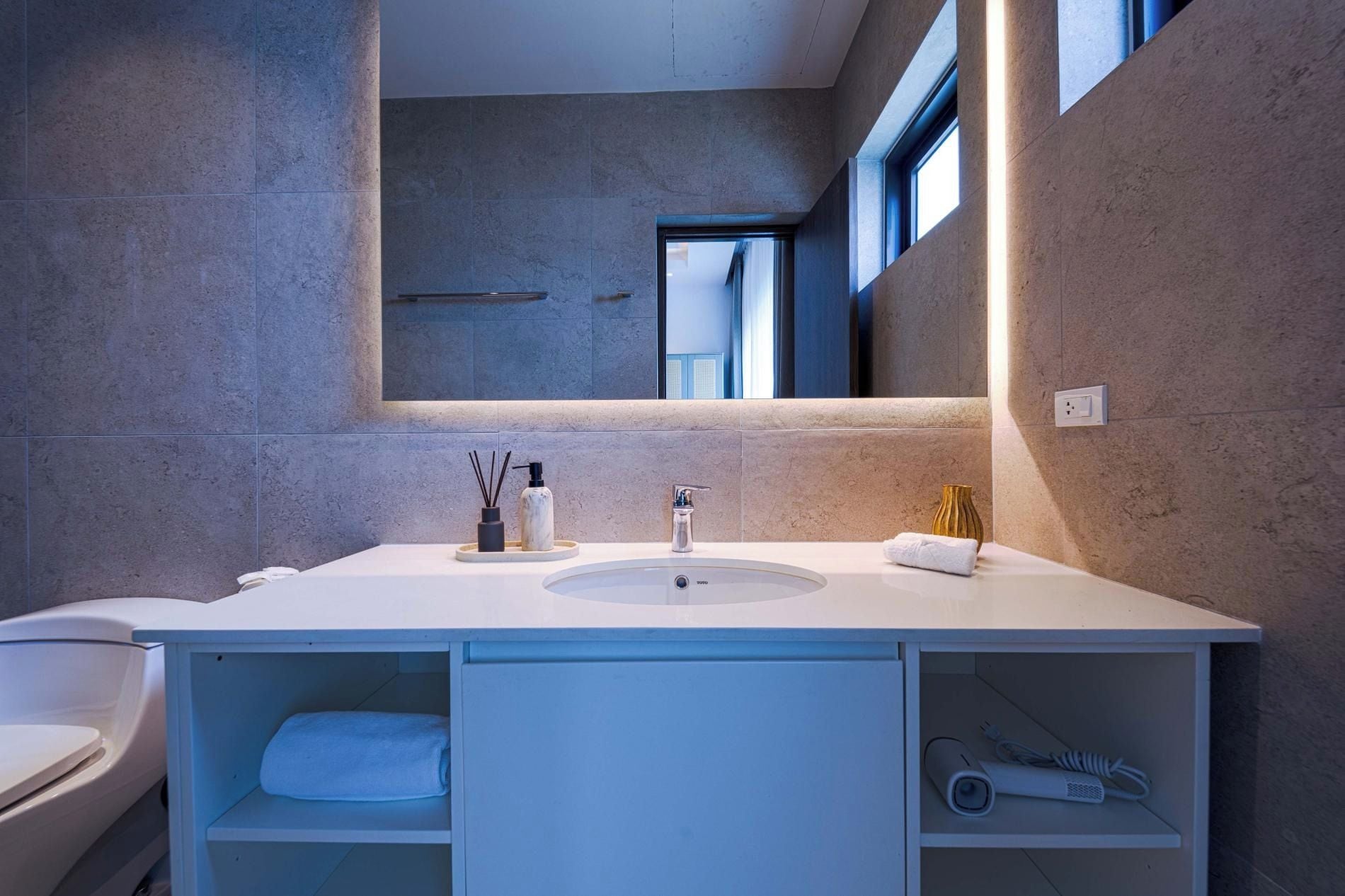 A modern bathroom with a large vanity, a mirror, and a window.