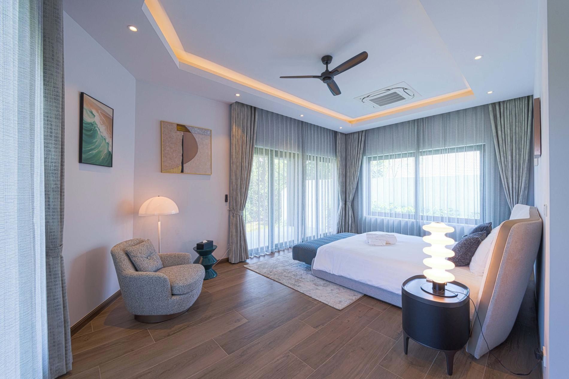 A modern bedroom with a bed, a ceiling fan, a standing lamp, and a window with curtains.