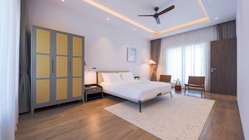 A hotel room with a bed, nightstands, a desk, a chair, a wardrobe, and a ceiling fan.
