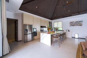 Una cocina moderna con una isla central, electrodomésticos de acero inoxidable y un ventilador de techo.