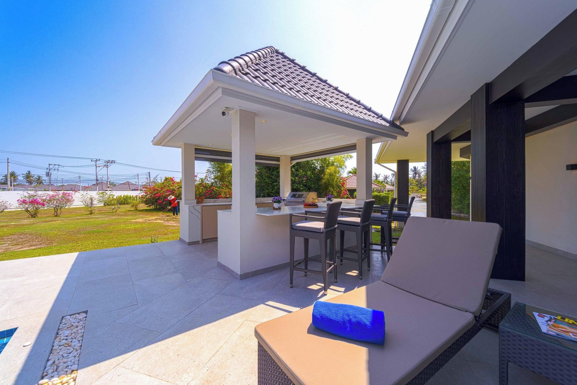 An outdoor patio with a covered seating area, a grill, and a pool.