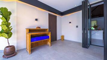 Ein modernes Interieur mit einer Holzbank, einer Topfpflanze und einer Glastür, die in einen Küchenbereich führt.