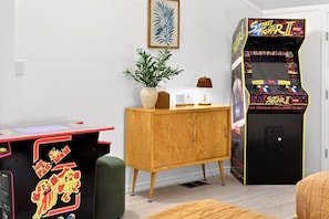 A room with a wooden cabinet, a small table, a plant, a lamp, and a Street Fighter II arcade machine. - HillCreek Villa - Spa • Sauna • Cold Plunge • Creekside Shower • Arcade Games (Redding)