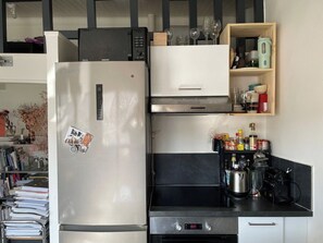 A kitchen with a stainless steel refrigerator, a coffee maker, and various kitchen utensils. - Designer apartment in the middle of Paris (Paris)