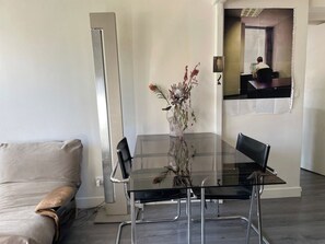 A modern living room with a glass dining table, a sofa, and a vase with dried flowers. - Designer apartment in the middle of Paris (Paris)