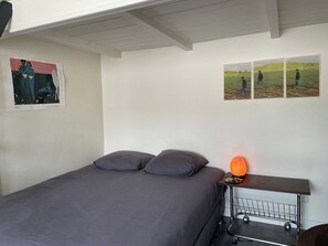 Un dormitori amb un llit, almoines, una tauleta de nit, un calefactor i decoració a la paret.
