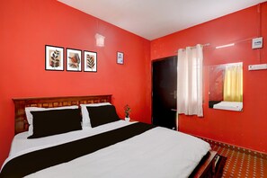 Ein Zimmer mit einem Bett, einer Tür, einem fensterbepflanzten Fenster und Wandbildern.
