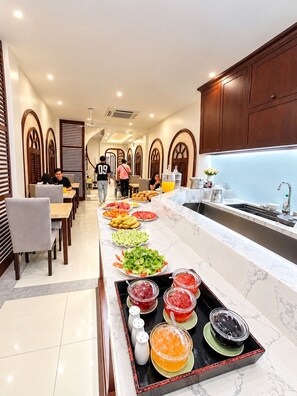 Espaço de refeições de hotel com serviço de buffet, incluindo diversas opções de comida e uma pia.