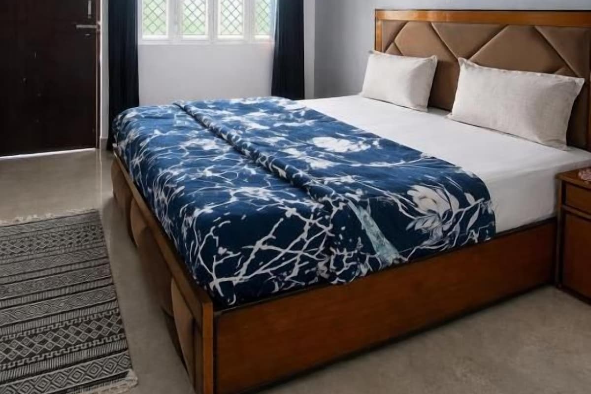 A bedroom with a bed, a ceiling fan, a window with curtains, and a door.