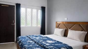 Un dormitorio con una cama, un ventilador de techo, una ventana con cortinas y una puerta.