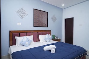 A neatly made bed with a blue bedspread and white pillows, a wooden headboard, and artwork on the walls. - Himalayan Nest Chopta (Ukhimath)