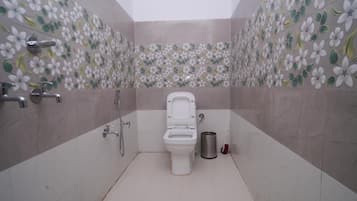 A bathroom with a toilet, a shower, and a hand dryer.