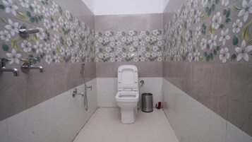 A bathroom with a toilet, a shower, and a hand dryer.