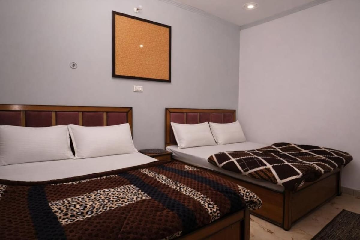 A hotel room with two beds, each with a headboard and pillows.
