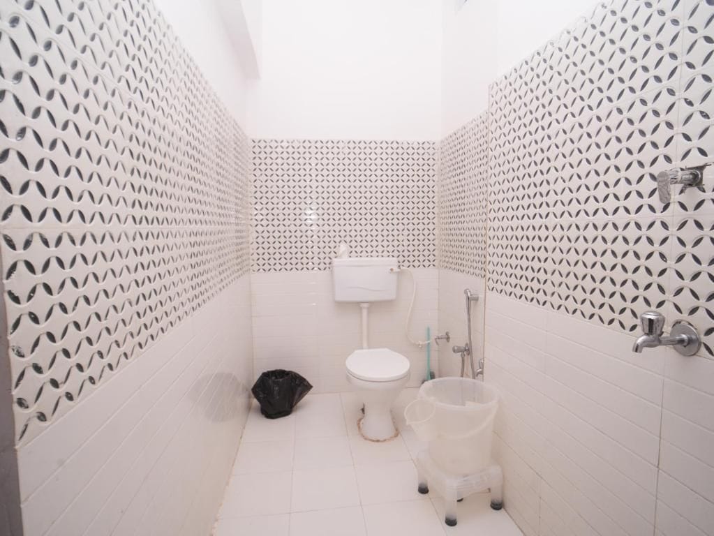 Un baño pequeño con inodoro, ducha y cubo de basura.