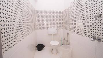 Un baño pequeño con inodoro, ducha y cubo de basura.