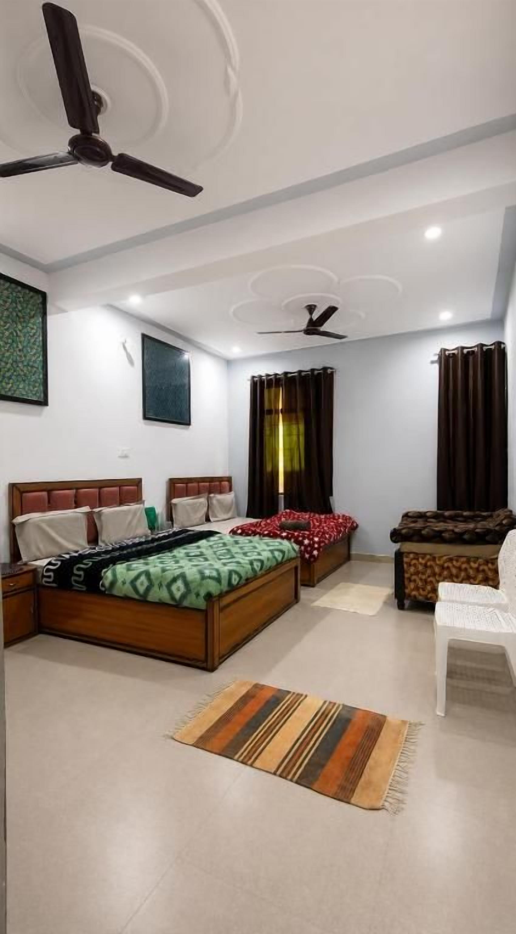 A bedroom with a bed, a chair, a ceiling fan, and a window with curtains.
