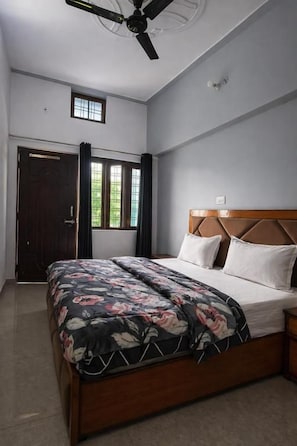 A bedroom with a bed, a ceiling fan, a window, and a door. - Himalayan Nest Chopta (Ukhimath)