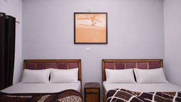 Habitación de hotel con dos camas, una mesita de noche, un cuadro enmarcado en la pared y una ventana con cortinas.
