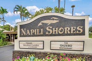 Schild für Napili Shores mit einer Delphin-Grafik, das eine Ferienwohnung und ein Restaurant anzeigt.
