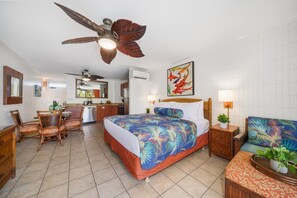 Ein Hotelzimmer mit Bett, Esstisch mit Stühlen, Deckenventilator, Küchenzeile und Badezimmer.