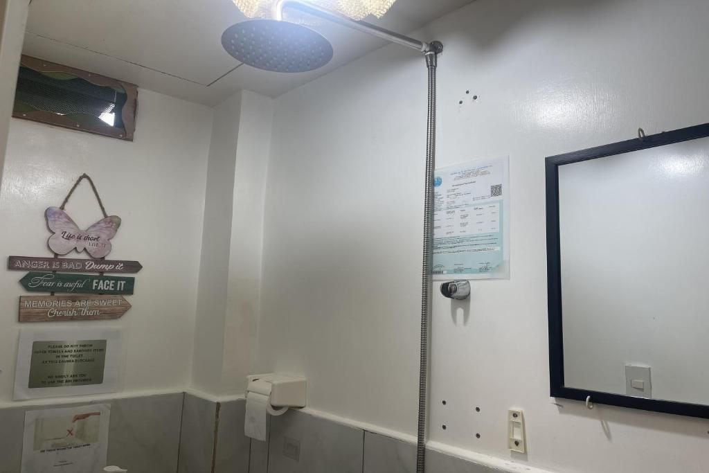 A bathroom with a shower, a toilet, and a mirror. There are motivational signs on the wall and a paper with text.